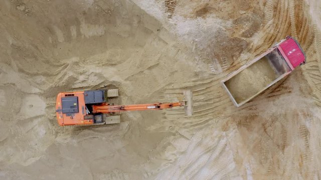 Aerial shot of empty truck pulls up to the excavator for loading. Excavation work for the construction of the road.