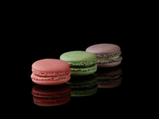 Multi-color macarons on the black background. Side view. Blank space.