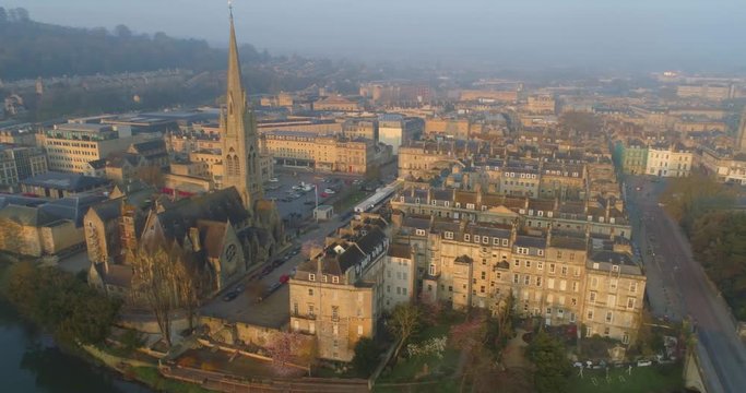 Aerial circling Bath's tallest spire of St John the Evangelist catholic church in the historic Roman city of Bath England amongst Georgian houses