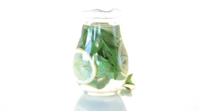 Fresh cold lemonade with lemons and mint in a carafe isolated on white