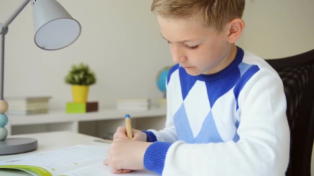 Teenage boy studying at desk in his room at home