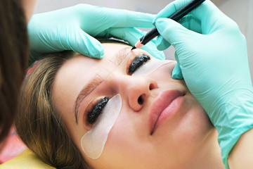 Beautiful Asian woman with long eyelashes in a beauty salon during eyelash extension. Eyelash...