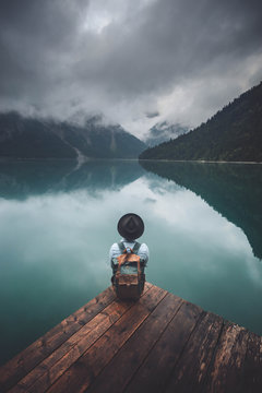 child sitting on wooden dock overlooking the lake