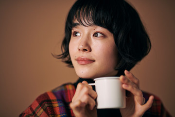  暖かい飲み物を飲む若い女性