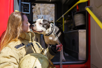 Photo of firewoman with dog standing near fire truck
