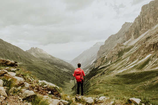 man standing on rock near rock mountain under gray sky during daytime