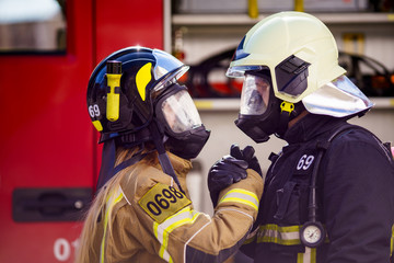 Photos of firefighters women and men in helmet and mask looking at each other and doing handshake near fire truck