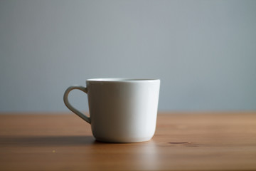 white coffee mug on wooden table and light background