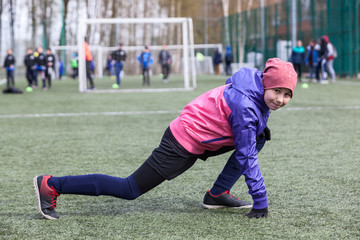 Obraz premium Eleven-year female football player does exercises for flexibility, warm-up before a match