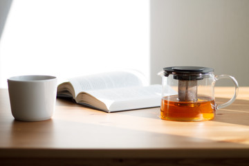 white coffee mug on wooden table and light background with book close-up kettle