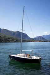 Beautiful landscape with sail boat moored near the coastline, lake and mountains.- Image