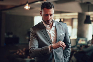 Portrait of young businessman in suit looking at his watch