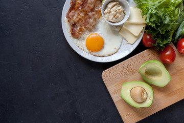 Keto food: egg, bacon, avocado, cream cheese, tomatoes and fresh salad. Healthy fats diet.  
