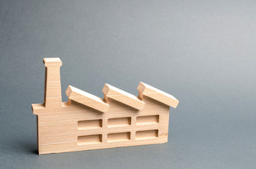 Wooden figurine of a plant or factory on a gray background. Recycling raw materials. The concept of industry and production.Investments in the construction of new factories.