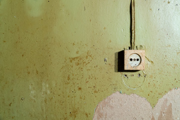 Old power socket isolated on damaged green wall - reconstruction background