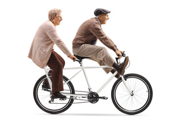 Senior man and woman riding a tandem bicycle with legs up