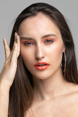 the girl keeps pressing her fingers against her head. Close-up portrait of the model on a gray background.