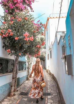 woman wearing dress walking near pink petaled flower
