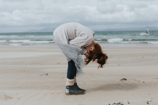 woman wearing gray jacket binding on sea shore