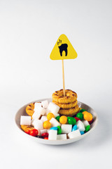 dental health concept: caries danger sign standing over a plate with cookies, sugar and sweets