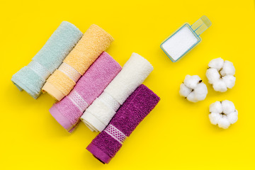 powder for laundry and cotton towels on yellow background top view