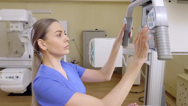 Beautiful Female Technician ajusts X-ray Machine