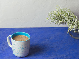 A Cup of coffee and a bouquet of lilies of the valley with copyspace