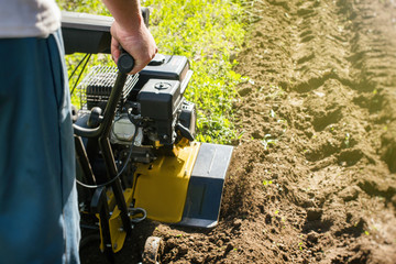 Fototapeta premium Outdoor garden plow job with a motor cultivator