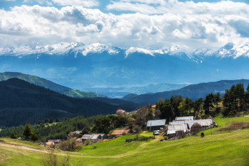 Fototapeta na wymiar Cloudy spring day over highest village on Balkans and Bulgaria - Ortsevo in Rhodope mountain. High snowy Pirin mountain at background.