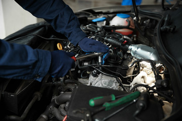 Fototapeta na wymiar Technician checking modern car at automobile repair shop, closeup