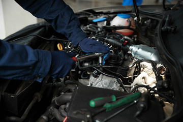 Technician checking modern car at automobile repair shop, closeup