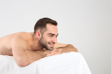 Obraz premium Handsome man relaxing on massage table against white background. Spa service