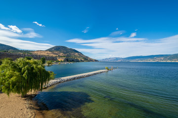 Magnificent view over Okanagan lake and valley with narrow foreland and clouds over blue sky