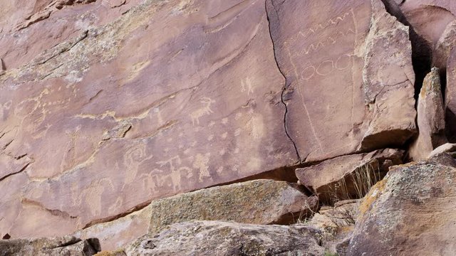 Wide panning view of petroglyphs on cliff in Nine Mile Canyon in Utah from native americans.
