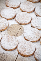 Fresh baked oat cookies with sugar powder on rustic wooden table background.