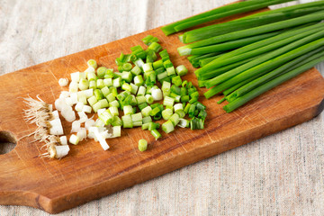 Chopped green onions on a rustic wooden board, side view. Close-up.