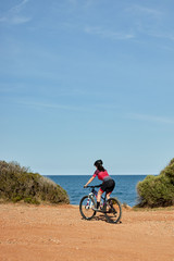 female cyclist with mountain bike on the coast