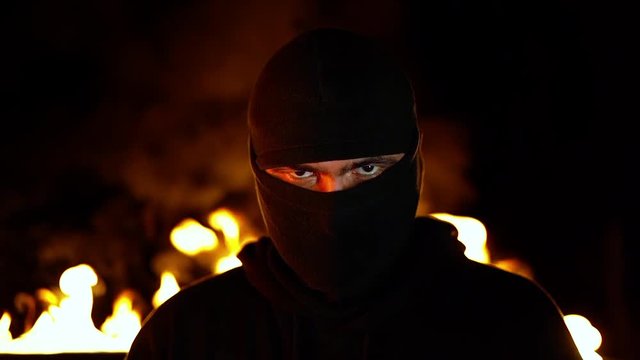 Portrait of protesting activist in mask against burning barricades at night. Concept of strikes, political conflicts and confrontation.