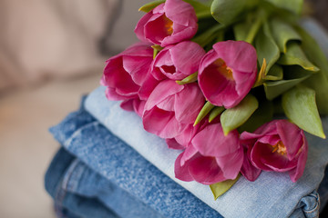 Close-up. A bouquet of tulips lying on a pile of jeans. Clothing.