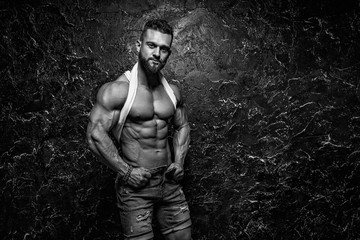 Portrait of strong healthy handsome Athletic Man Fitness Model posing near dark wall