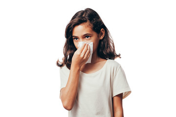 Sick little girl blowing her nose and covering it with handkerchief