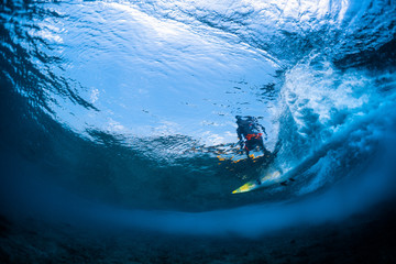 Underwater view of the surfer riding the crystal clear ocean wave