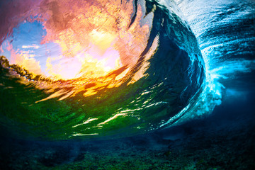 Underwater view of the crystal clear ocean wave barreling over the coral reef with clouds and...