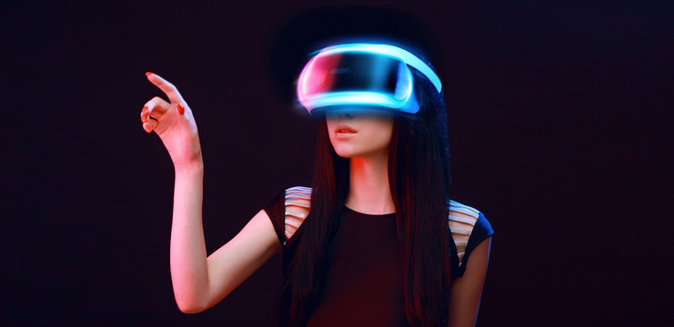 Model young woman in glasses of virtual reality on dark background.. Augmented reality, science, future technology concept. VR. Futuristic 3d glasses with virtual projection. Neon light.