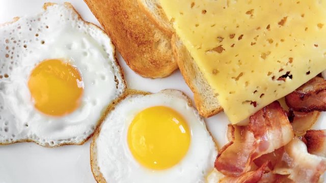 View from above fresh tasty fried toasts with cheese and frying egg with bacon on plate