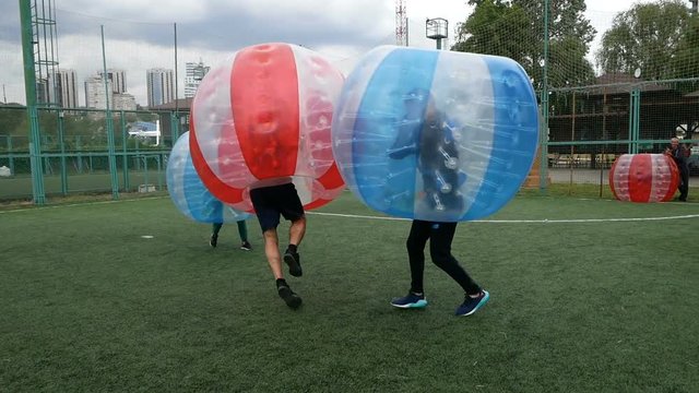 People play bumperball zorbsoccer outdoor. summer time.