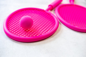 Two fuchsia pink beach tennis rackets and ball