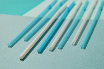 White and blue plastic tubes, turquoise tone. Selective focus, top view.