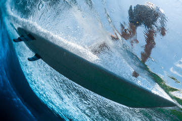 Underwater view of the surfer riding the crystal clear ocean wave