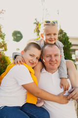 young family dad mom son and daughter are walking the street in the park at sunset and having fun